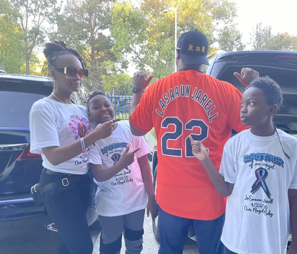 A family wearing Brother of an Angel shirts and a LaSaaun Jarell 22 jersey in remembrance